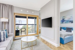 A sophisticated living room with a modern gray sofa, a round marble coffee table, and ambient lighting, providing a cozy yet elegant atmosphere.