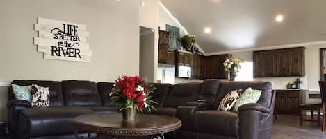 Living room includes leather sectional and flat screen TV