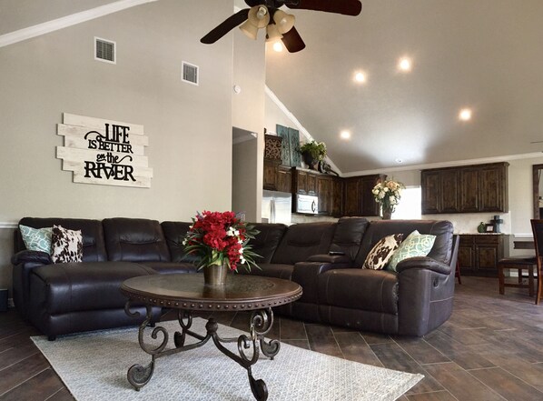 Living room includes leather sectional and flat screen TV