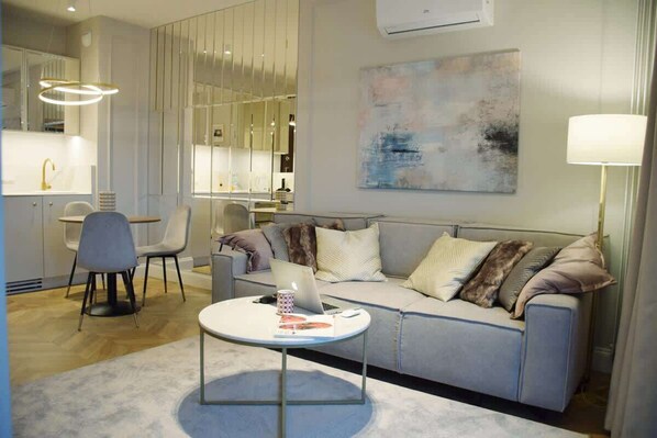 A cozy living room with a modern gray sofa, elegant throw pillows, a round coffee table, and soft ambient lighting, creating a warm atmosphere.