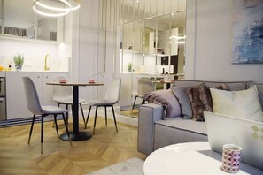 A stylish living room with a wall-mounted TV, chic decor, and an open layout connected to a dining area, giving a spacious feel.