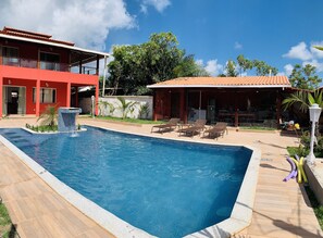 Piscina com  cascata e cadeiras de sol 