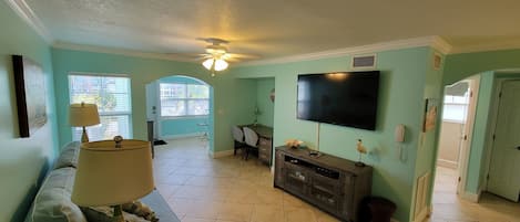 Main living room area with queen sofa bed, desk/work station, TV and wet bar.