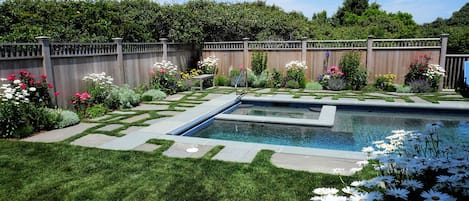 Private heated salt water pool and jacuzzi set in perennial flower garden.