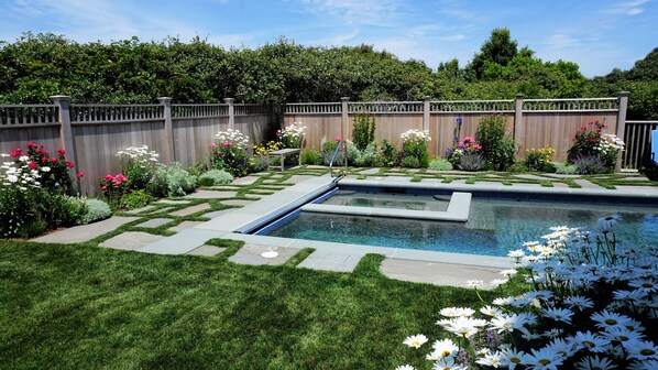 Private heated salt water pool and jacuzzi set in perennial flower garden.