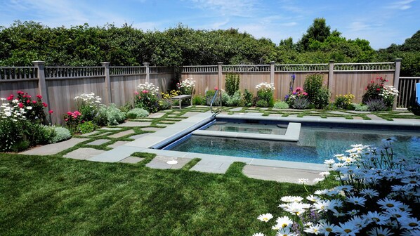 Private heated salt water pool and jacuzzi set in perennial flower garden.