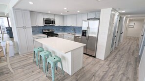 Full kitchen w/ quartz countertops and stainless steel appliances.