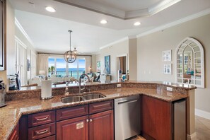 Adagio B201 kitchen with view of the Gulf - Well-stocked kitchen with dishwasher, stand alone ice maker, microwave, oven/stove, large refrigerator and plenty of dishware, cookware and bakeware for your family and friend's visit. Your Friend At The Beach provides each of our Adagio condos with all you need - even a crockpot and a keurig (plus a regular coffee maker)