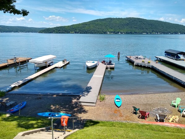 View of beach, fire pit, and dock from porch