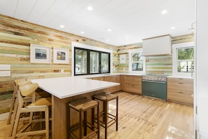 The centerpiece of the remodeled, fully furnished kitchen is a green induction oven. It has a peninsula that seats five, a beverage station, and a walk-in pantry.