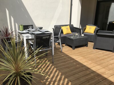 Grande terrasse ensoleillée avec salon de jardin, table repas et parasol