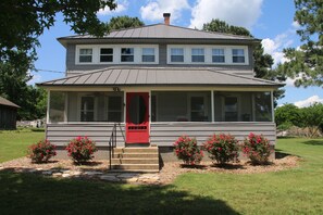 The front of The Farm House with screened porch with rocking chairs ..