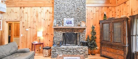 Stacked stone fireplace, smart tv, misc games, cozy sofa, loveseat, and chairs