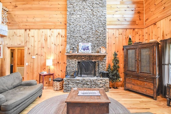 Stacked stone fireplace, smart tv, misc games, cozy sofa, loveseat, and chairs