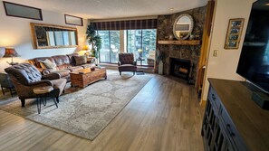 Living room with wood fireplace, dining table, and balcony w/ propane BBQ grill