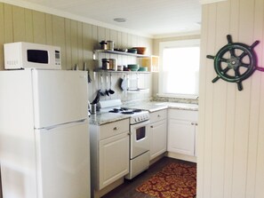 Kitchen fully equipped with pots, pans, dishes and utensils.