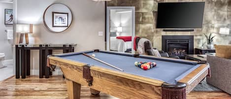 Pool table with living room in background along with fireplace & 75" OLED TV.