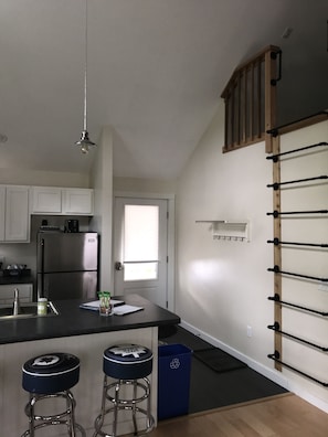 View from living area to entry, loft ladder and part of kitchen