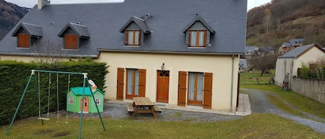 maison clôturée avec salon de jardin, balançoire et maison d'enfants