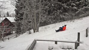 les enfants font de la luge dans le jardin en pente sous surveillance