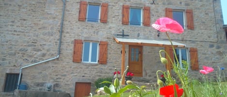 façade du gîte  avec la fontaine sur la gauche ou l'eau coule encore et encore . 