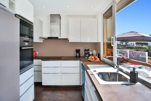 Espace cuisine avec un frigo américain, accès direct sur la terrasse repas a l'extérieure.