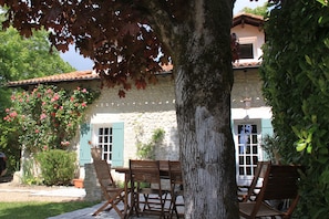 Terrasse ombragée avec son salon de jardin. Arrière de la maison 