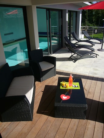 Terrasse couverte donnant sur la piscine et le jardin.