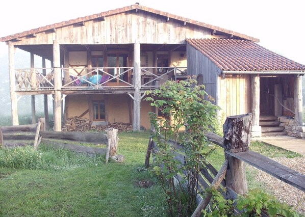 Maison écologique en ballots de paille recouverte de terre, son balcon de 120m2