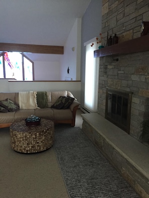 VAULTED LIVING ROOM WITH WOOD BURNING FIREPLACE, LOOKING INTO VAULTED FOYER