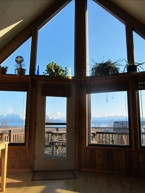 Vaulted ceilings and south-facing windows in living room leading outside to deck