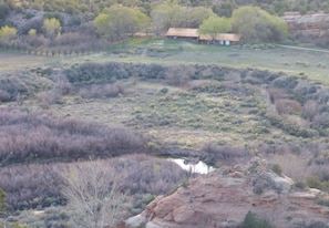 Moki Point Ruins in foreground & Apple & Elm trees, Cabin, and red rock in back
