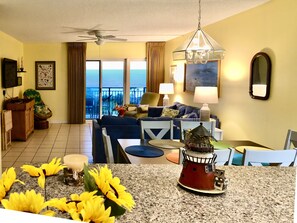 Living room & dining area from kitchen. Balcony access & Gulf in background.