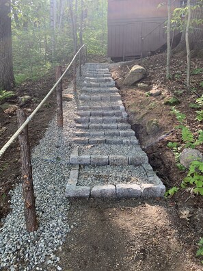 The path to the dock slopes down through the woods .  Steps lead to the lake.