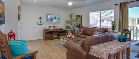 Vantage point from dining table and seating toward kitchen, living room and TV. Wood-look laminate flooring throughout.