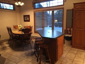 Kitchen island with 4 seats and dining room table with 6 seats - entry to deck.