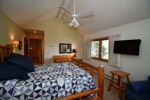 Master bedroom queen, large TV, and fan.