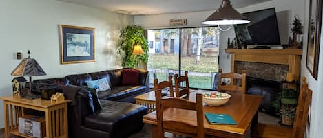 Living room with sofa bed, dining table, gas fireplace, and patio w/ gas BBQ