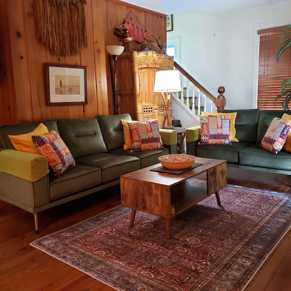 Spacious retro-themed living room, with velvety sofa and loveseat. 