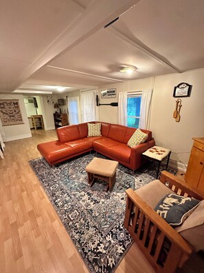 Living room with comfy pit couch and rocking chair with ottoman and tv. 