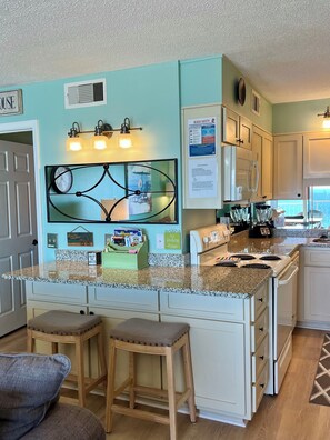 Queen sofa bed linens and pillows in cabinet behind stools.  