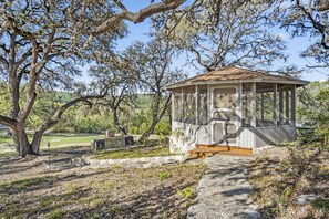 Charming screened-in gazebo nestled under majestic oaks-perfect for peaceful mornings or relaxing evenings outdoors.