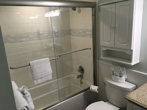 Updated master bath with tub and glass shower doors.