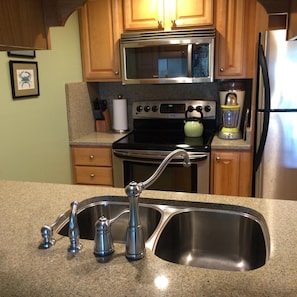 Kitchen wok area with stainless steel appliances and Silestone counters