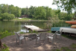 View of firepit, watercraft, dock and river from lawn in late spring.