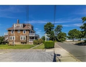 View of the house and parking area with Good Harbor Beach in the background.