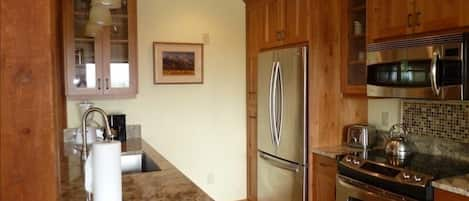 Kitchen with new stainless appliances, cherry cabinets, and granite countertops.