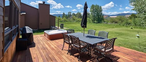 Hot tub, grill, dining table & umbrella overlooking open space