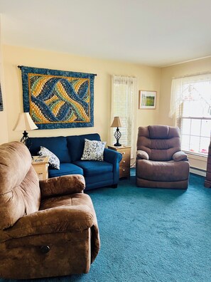 Living room with 2 electric recliners and also has an air conditioner.