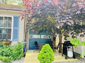 A small deck with a gas grill and and table and chairs for out door dining.